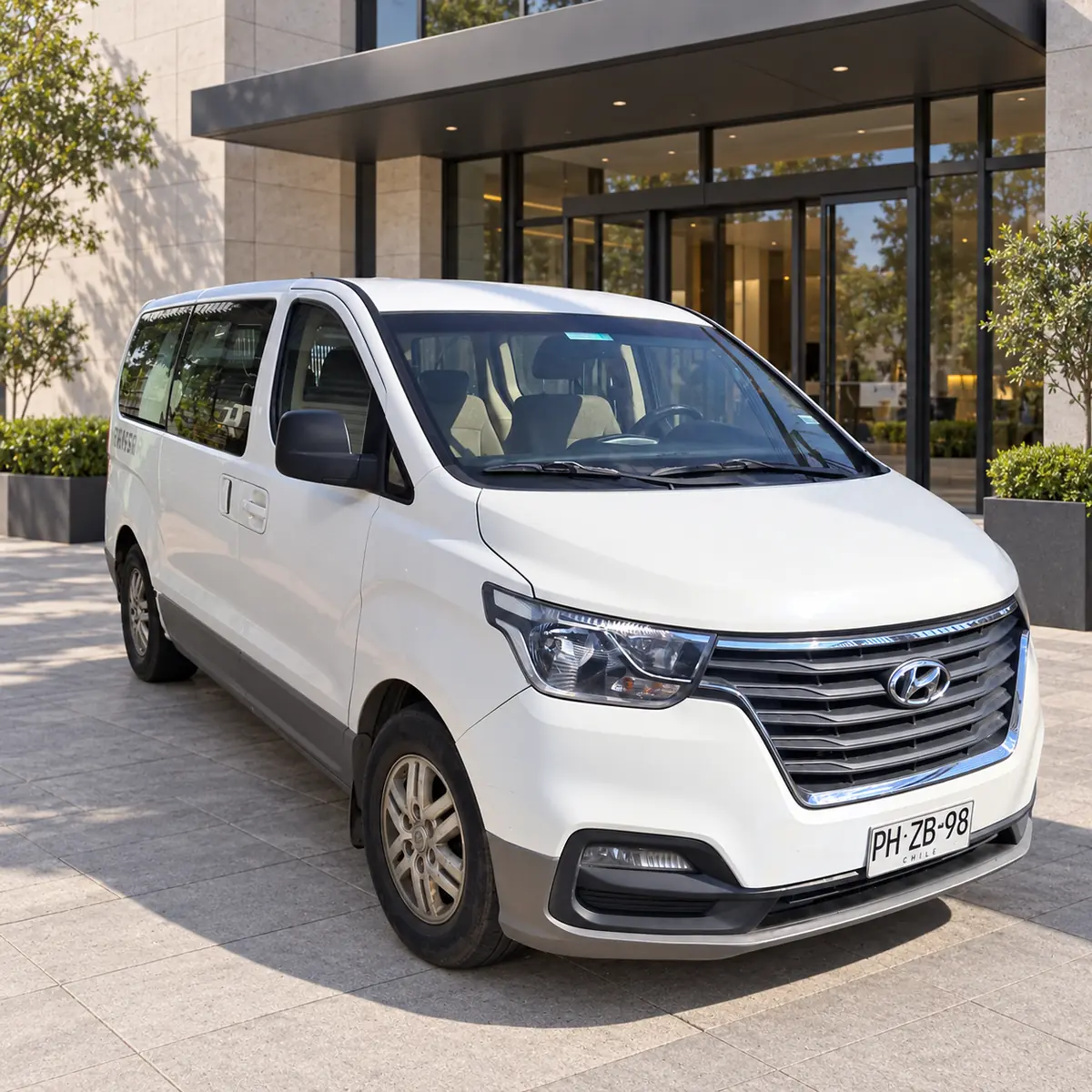 Hyundai H1 blanca, vista frontal y lateral junto a un hotel